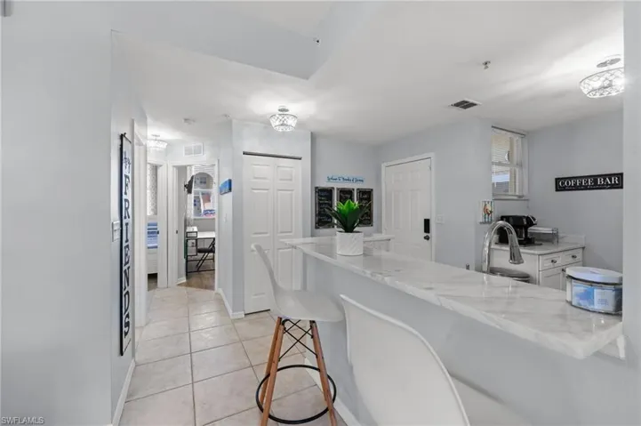 Kitchen featuring a stone countertop, a stainless steel sink with a high-arc faucet, and overhead lighting fixtures