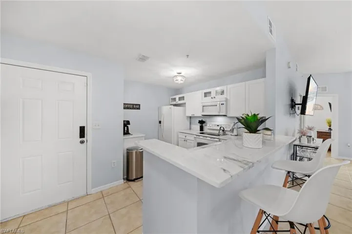 The property features a kitchen with white cabinetry, a white refrigerator, a white microwave, and a white oven/stove