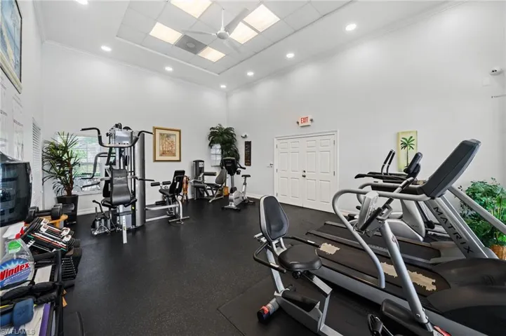 The property includes a fitness area with various exercise machines, resilient flooring, and an abundance of overhead lighting, ensuring a bright and functional workout space
