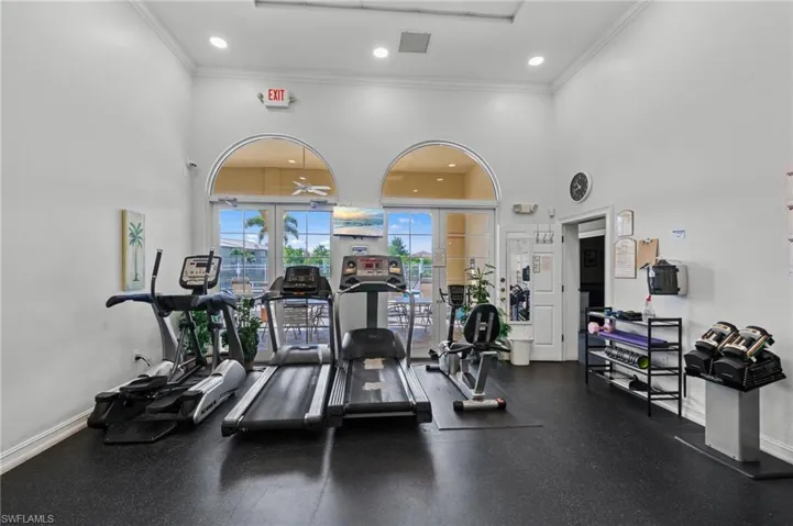 Fitness room featuring high ceilings, arched doorways, exercise equipment, and a view of outdoor patio