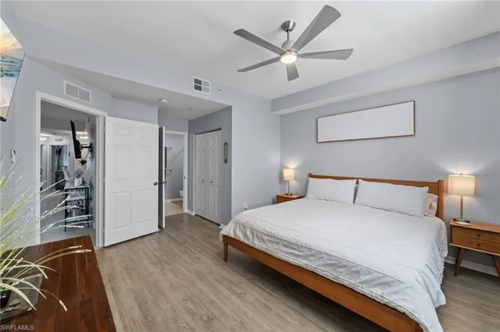 Bedroom featuring light wood-style flooring, a ceiling fan with integrated lighting, and light blue walls