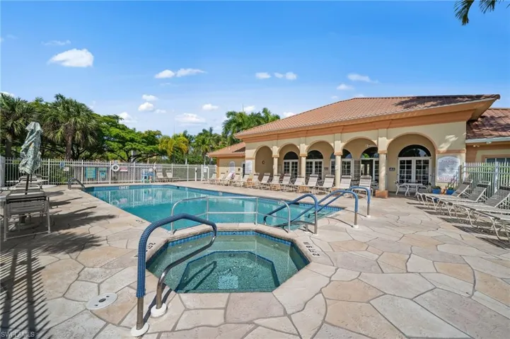 The property features a large swimming pool and a separate spa, surrounded by an expansive stone patio