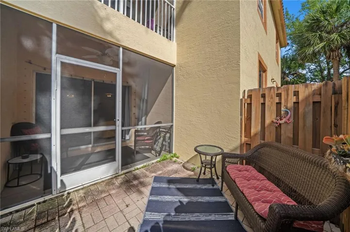 Patio area featuring a screened enclosure, pavers, and a wooden fence
