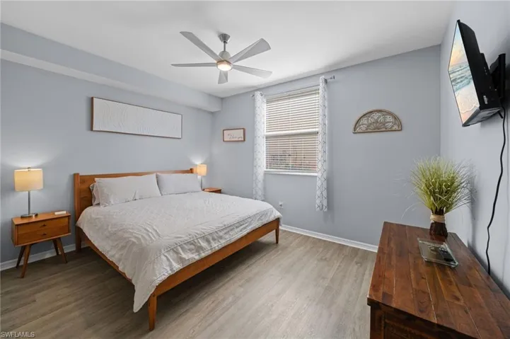 This room features light-toned flooring, a window with blinds and curtains, and a ceiling fan
