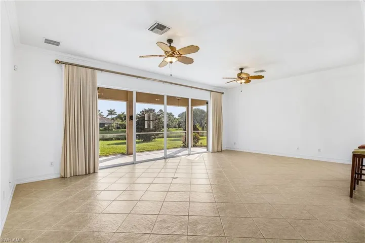 Empty room with ceiling fan, light tile patterned flooring, and ornamental molding