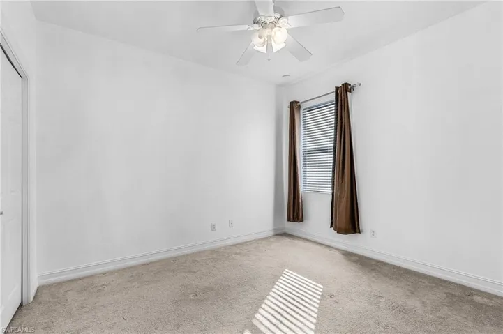 Carpeted empty room featuring a ceiling fan and baseboards