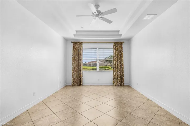 Unfurnished room with a tray ceiling, ceiling fan, and light tile patterned floors
