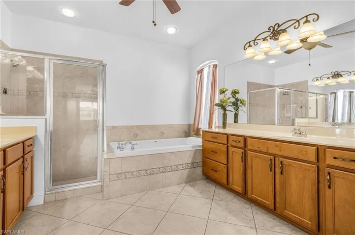 Bathroom with ceiling fan, vanity, a garden tub, a shower stall, and tile patterned flooring