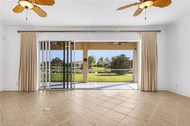 Empty room featuring a ceiling fan, tile patterned floors, and crown molding