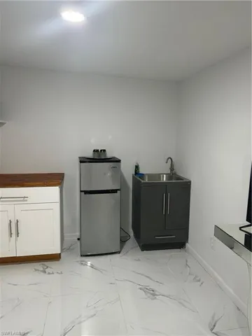 The property features white walls, a single ceiling light fixture, and white tile flooring with a grey veined pattern