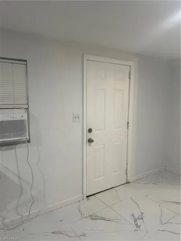 The room features white walls, a white paneled door, and white floor tiles with grey veining