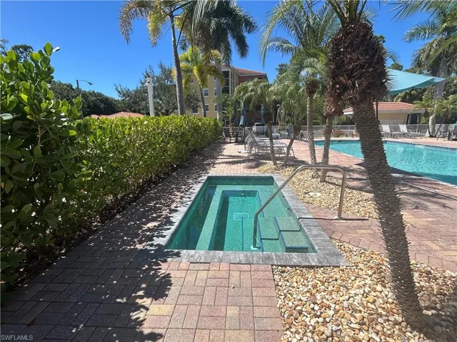 Community pool with a patio and a hot tub