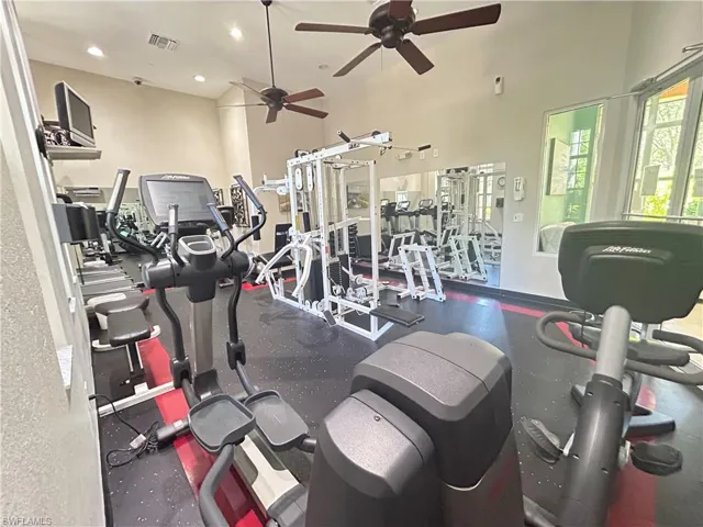 Exercise room with a towering ceiling, recessed lighting, and a ceiling fan