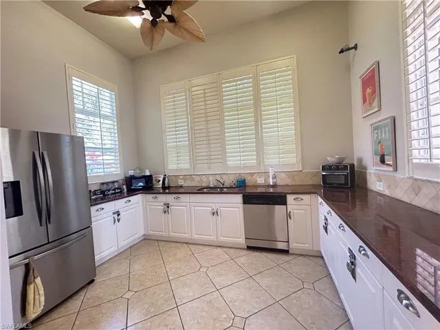 Kitchen with appliances with stainless steel finishes, white cabinetry, dark stone countertops, and a ceiling fan