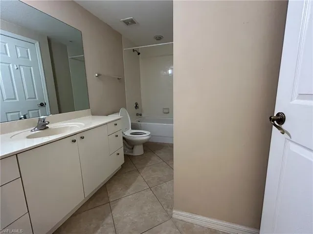 Bathroom featuring shower / bath combination, vanity, and light tile patterned flooring