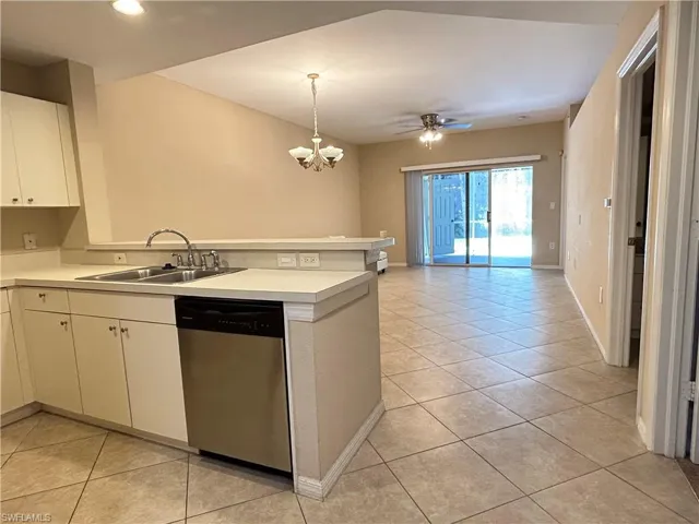 Kitchen with light countertops, stainless steel dishwasher, light tile patterned floors, pendant lighting, and white cabinets