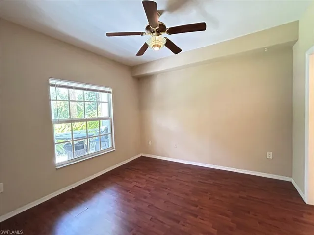 Unfurnished room with dark wood-style flooring and ceiling fan