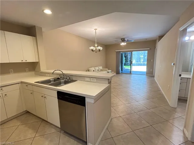 Kitchen with open floor plan, light countertops, dishwasher, light tile patterned floors, and white cabinetry