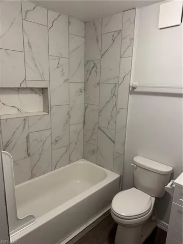 Primary Bathroom with washtub / shower combination with built-in niche, and vanity. Dark wood LVP floors