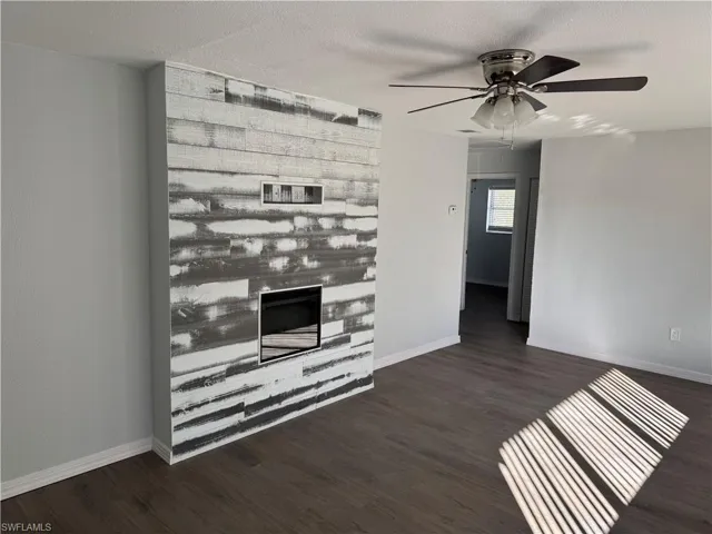 Living area with wood-style LVP floors, a glass covered fireplace, and ceiling fan