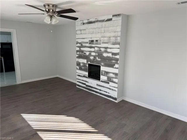 Living area with wood-style LVP floors, a glass covered fireplace, and ceiling fan