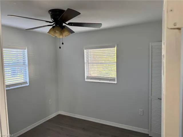 Unfurnished Back Guest bedroom with dark wood-style LVP flooring, a ceiling fan, and plenty of natural light