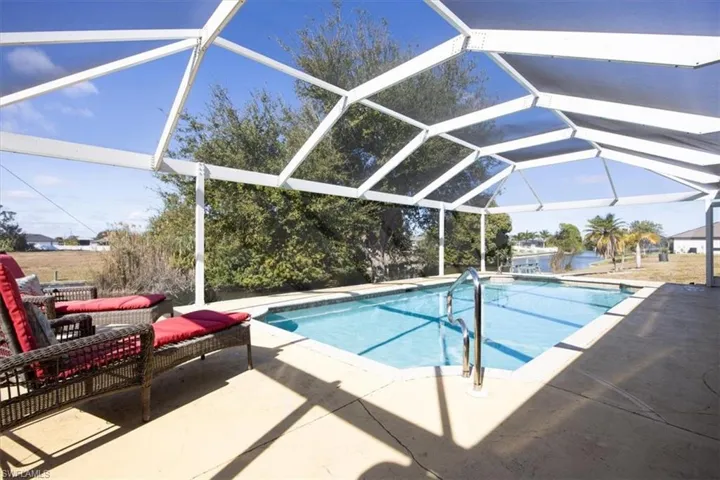 Outdoor pool featuring glass enclosure, a sunroom, and a patio area