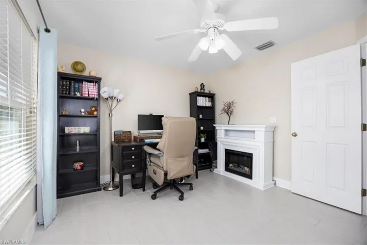 Home office with ceiling fan and a glass covered fireplace