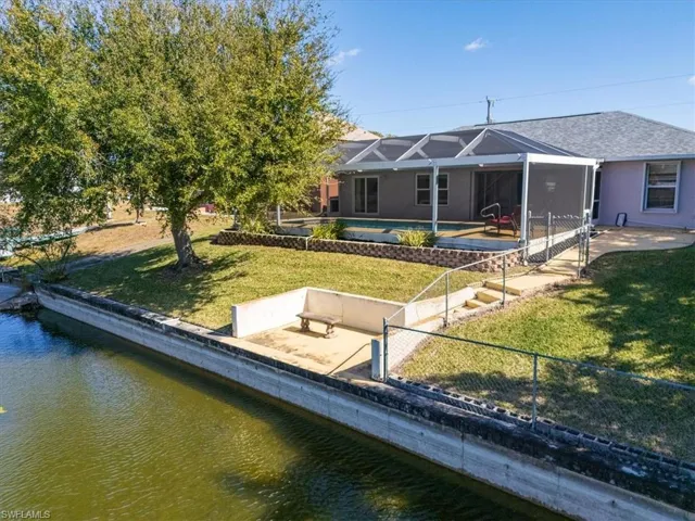 Rear view of house featuring a sunroom, glass enclosure, a patio, an outdoor pool, and a water view