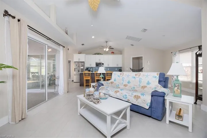 Living room with lofted ceiling, recessed lighting, and ceiling fan