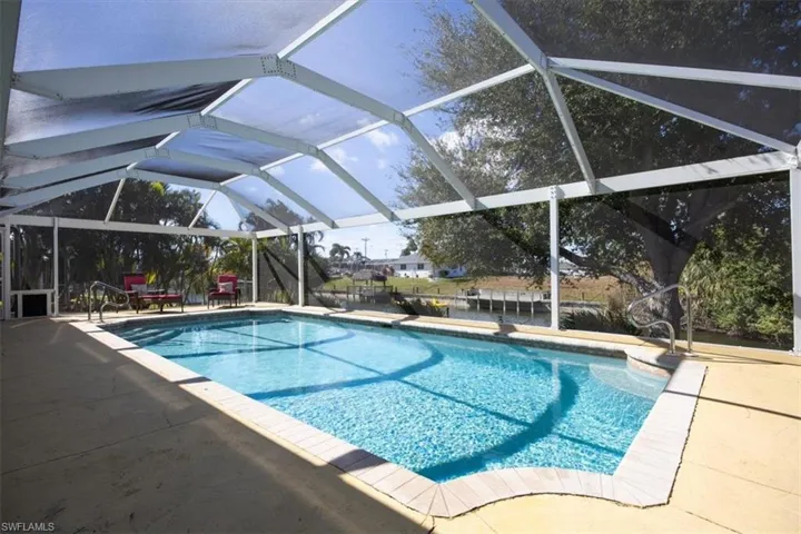 Outdoor pool with glass enclosure, a patio area, and a sunroom