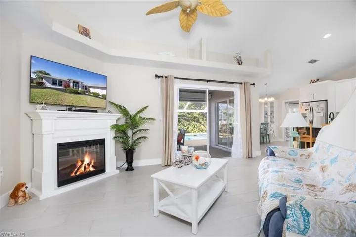 Living room with a glass covered fireplace, recessed lighting, and a ceiling fan