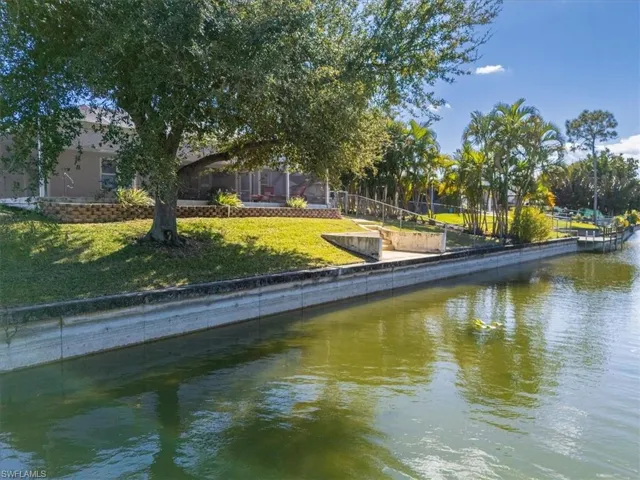 Dock featuring a water view, a lawn, and a sunroom