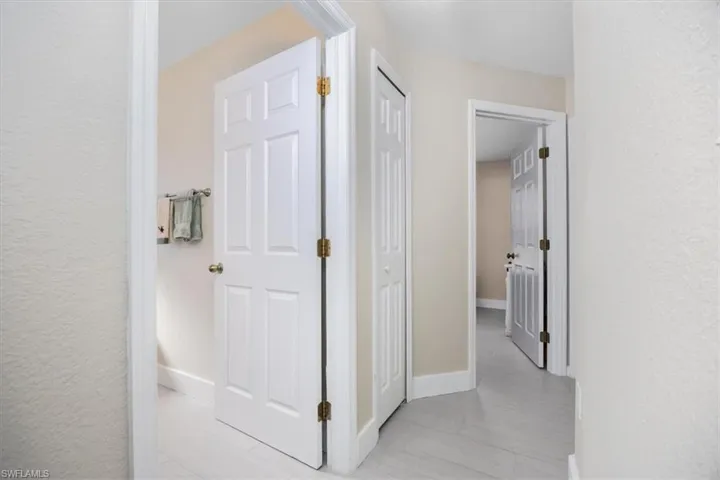 Hallway with a textured wall and baseboards