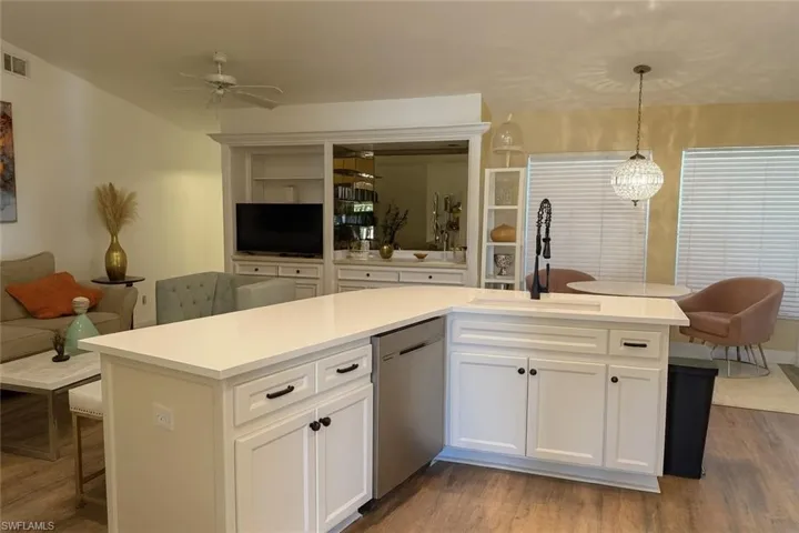 Kitchen with white cabinets, a kitchen breakfast bar, open floor plan, stainless steel dishwasher, and pendant lighting