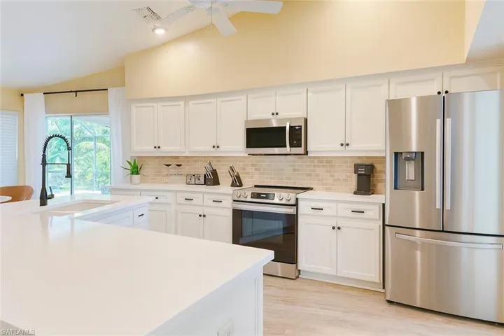 Kitchen featuring stainless steel appliances, white cabinets, tasteful backsplash, light quartz countertops, and recessed lighting