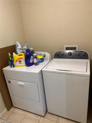 Washroom with light tile patterned flooring and independent washer and dryer