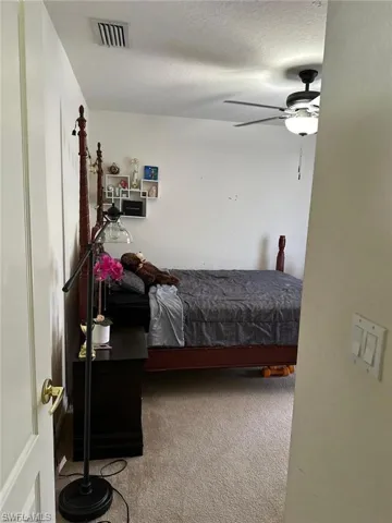 Carpeted bedroom featuring ceiling fan and a textured ceiling