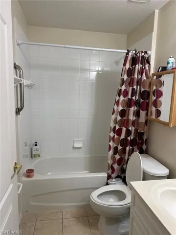 Full bathroom featuring vanity, shower / bath combination with curtain, tile patterned flooring, toilet, and a textured ceiling
