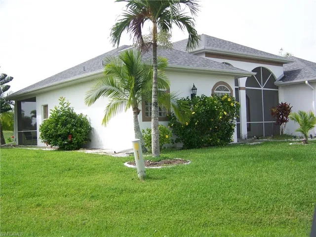 View of property left side exterior with concrete curbing and rear screened lanai