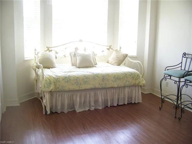 Guest bedroom #1 with wood-like flooring & lots of windows.