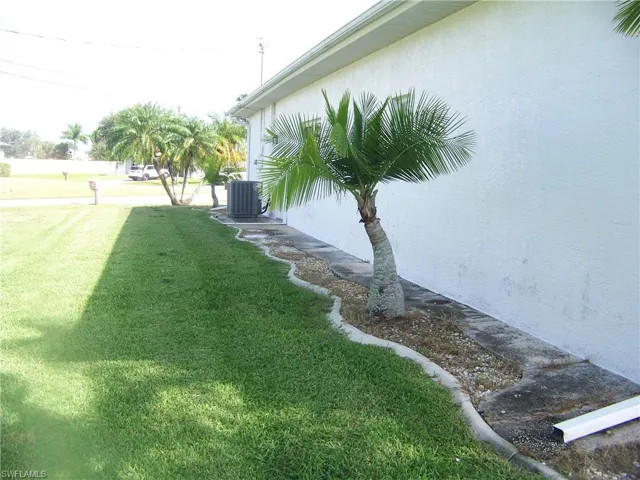 Side of home with concrete curbed garden featuring cooling unit