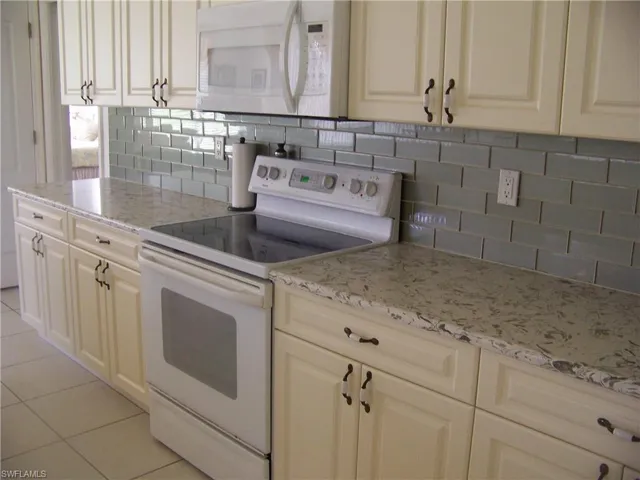 Kitchen with glass subway type tile, solid counter tops and numerous cabs.