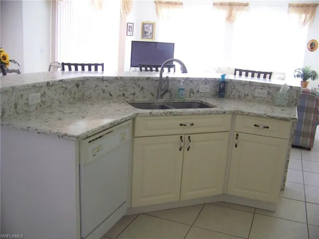 Kitchen with sink, light solid surface counters, dish washer & cabs.