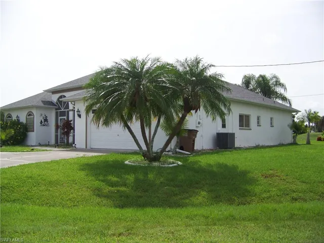 View of front facade with cooling unit, a garage, and a front lawn
