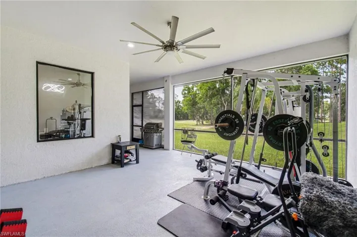 Screened enclosure with a ceiling fan, textured walls, and a reflective panel
