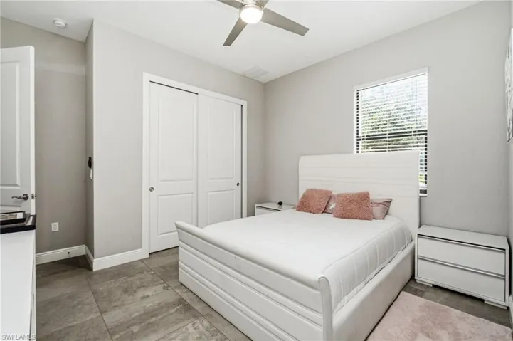 Overhead ceiling fan, window with blinds, double sliding closet doors, and tile flooring