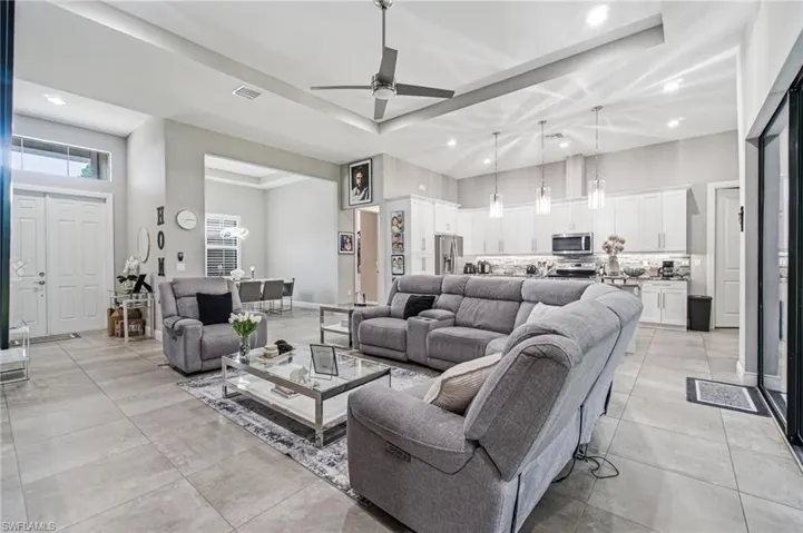 Open-concept living space featuring high ceilings with tray details, recessed lighting, and tile flooring