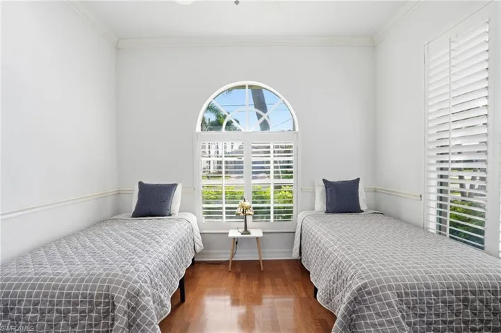 Bedroom with dark wood finished floors, ornamental molding, and ceiling fan