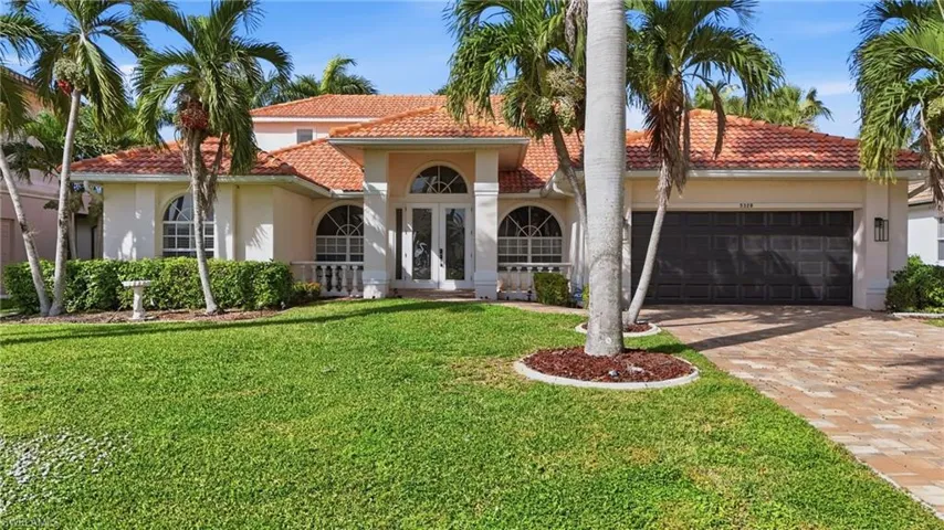 Mediterranean / spanish-style house with a tile roof, stucco siding, decorative driveway, a front yard, and a garage